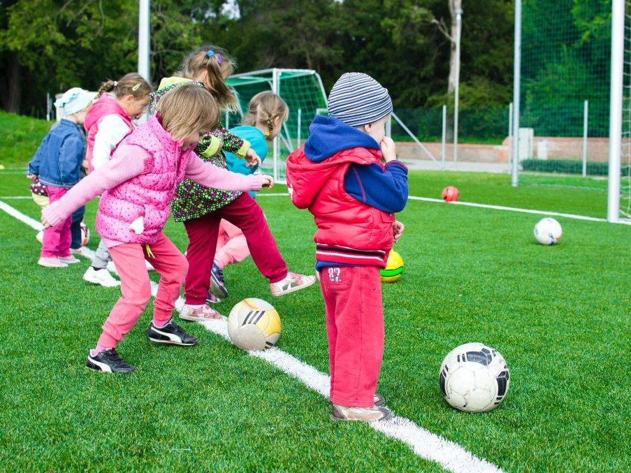 Na zdjęciu dzieci grajace w piłkę nożną fot. pexels