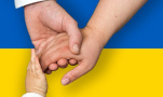 Ręce dwojga dorosłych i dziecka na tle flagi Ukrainy, fot. Pixabay