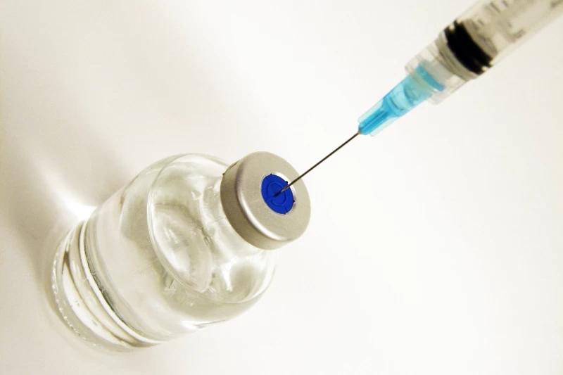 Na zdjęciu ampułka ze szczepionką i strzykawką