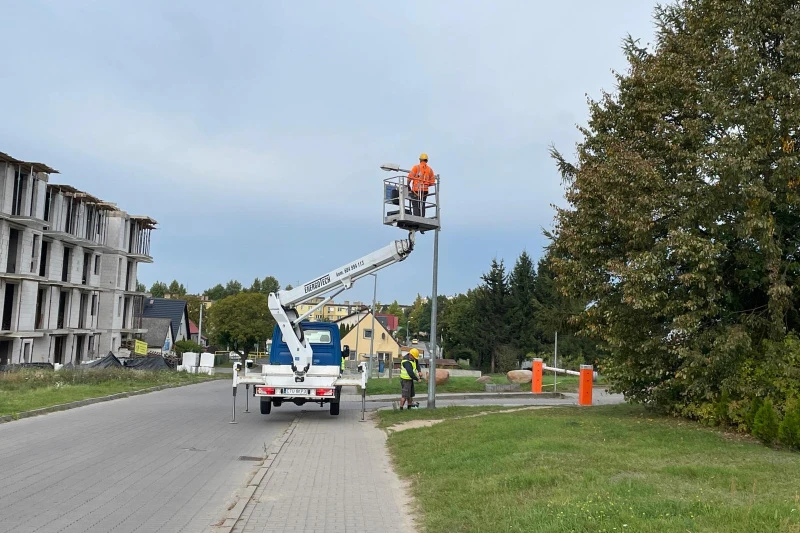 Zdjęcie przedstawia montaż nowych opraw oświetleniowych przez pracowników firmy energetycznej